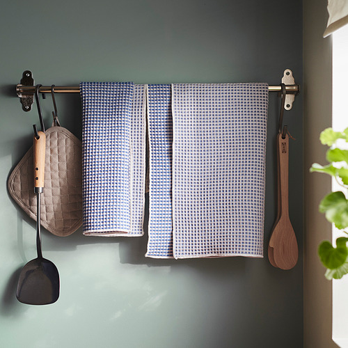 Estante de pared con paños de cocina colgantes, guantes de cocina y utensilios de madera.