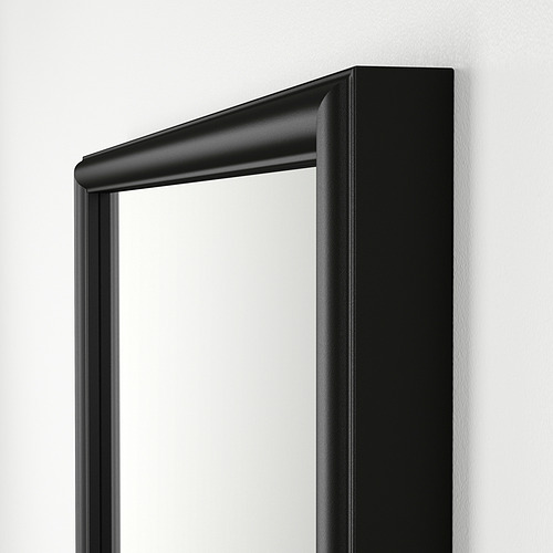 Elegante y moderno espejo con marco negro y bordes lisos, montado sobre una pared clara.