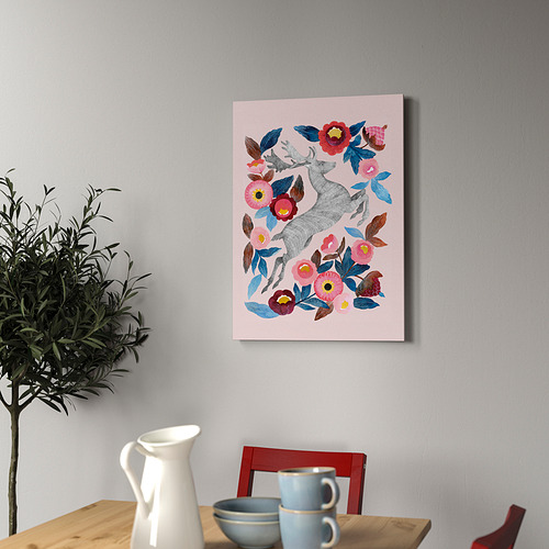 Lámina con ciervos y flores, enmarcada en la pared, junto a una mesa de madera con plantas, tazas y cuenco.