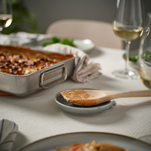 Mesa de cocina con plato horneado, copa de vino y soporte para cucharas.