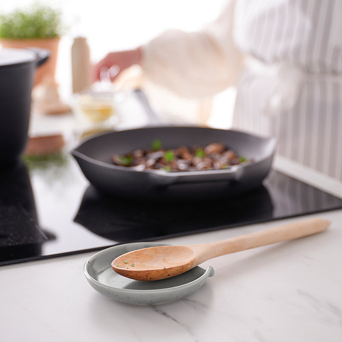 Cocina con sartén de champiñones salteados, reposacucharas.