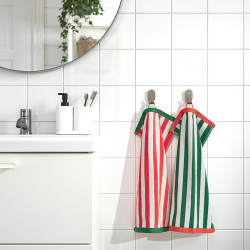 Las toallas SLÅNHÖSTMAL de rayas rojas y verdes brillantes cuelgan junto al lavabo y el espejo blancos.