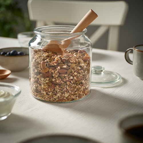 Tarro de nueces y semillas con cuchara sobre la mesa.