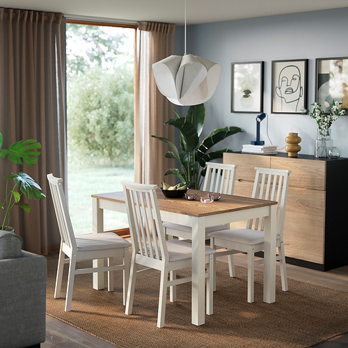 Mesa de comedor ÅLHULT blanca con tapa de madera, rodeada de sillas a juego en una acogedora zona de comedor.
