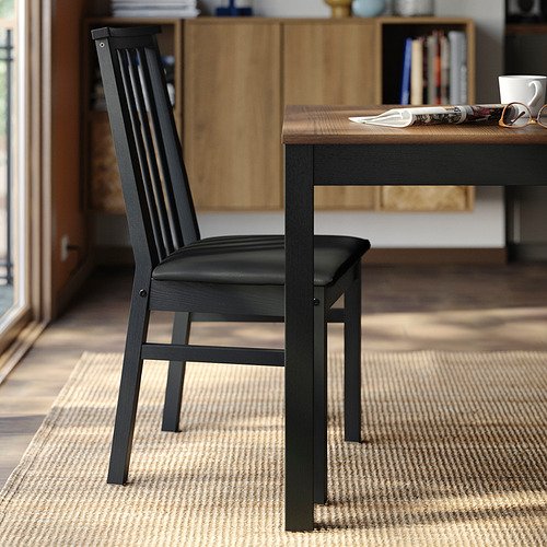 Silla de comedor negra moderna, asiento acolchado, respaldo en ángulo, estructura de madera robusta.