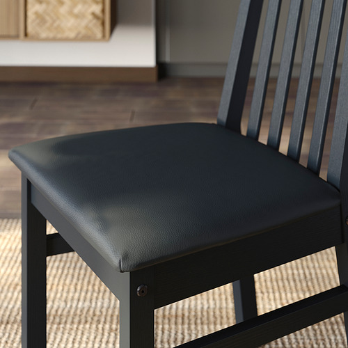Silla acolchada negra con respaldo de listones y estructura de madera, que ofrece comodidad y durabilidad.