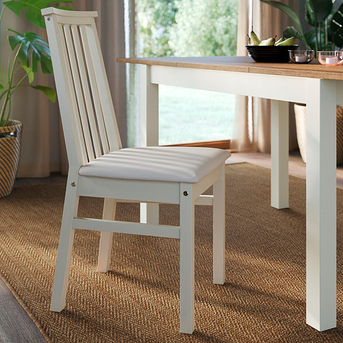 Silla de comedor moderna con respaldo de listones, asiento acolchado y estructura de pino resistente, colocada cerca de una mesa de madera.