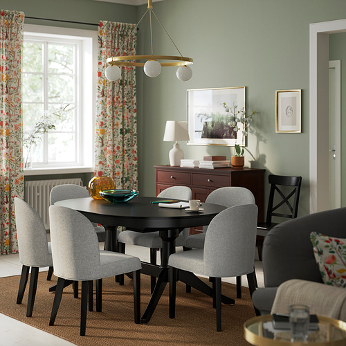Comedor moderno con sillas grises ROSENTORP, mesa negra, cortinas florales, paredes verdes y luz colgante. Sillas tapizadas en poliéster reciclado.