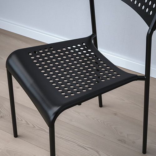 Silla moderna negra con asiento y respaldo perforados para ventilación, colocada sobre suelo de madera clara.