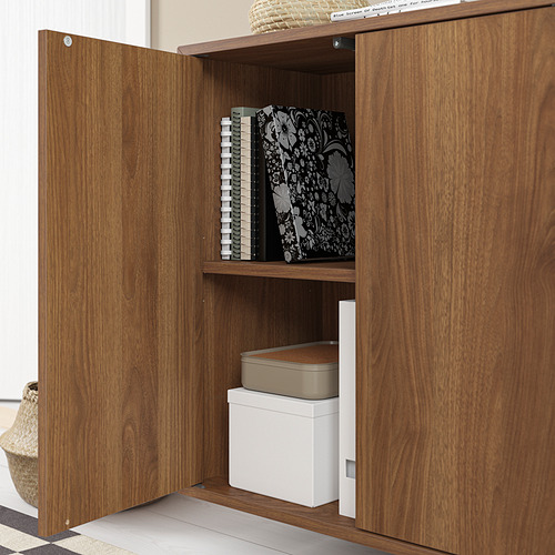 Un armario EKET de madera con una puerta abierta, que revela estantes con cajas de almacenamiento y libros.