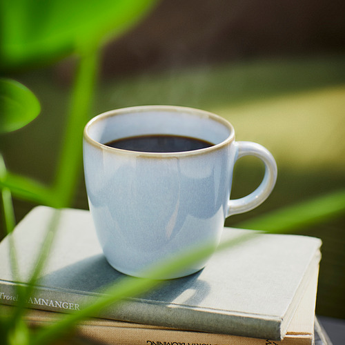 Taza blanca con café en libros. Diseño sencillo y artesanal.