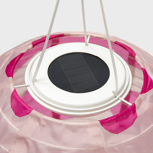 Lámpara colgante alimentada por energía solar con tiras de tela rosa, marco blanco y panel solar central.