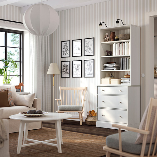 Sala de estar con arcón blanco HAVSTA, silla, estantería y mesa de café.