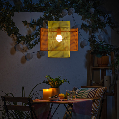 Acogedora escena de patio con luz colgante, velas y plantas.