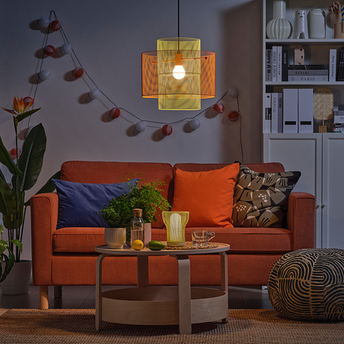 Sofá naranja, almohadas, mesa de centro, guirnalda de luces, planta, decoración.
