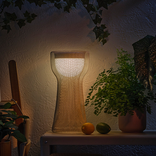 Una lámpara decorativa en una estantería con frutas y plantas, que emite un cálido resplandor.