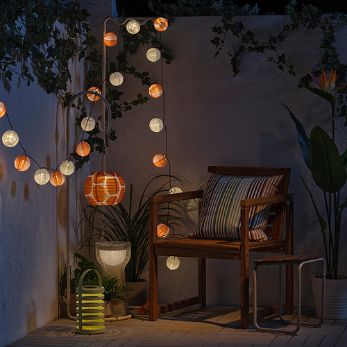 Acogedor patio con guirnaldas de luces, silla de madera y plantas. Ideal para relajarse.