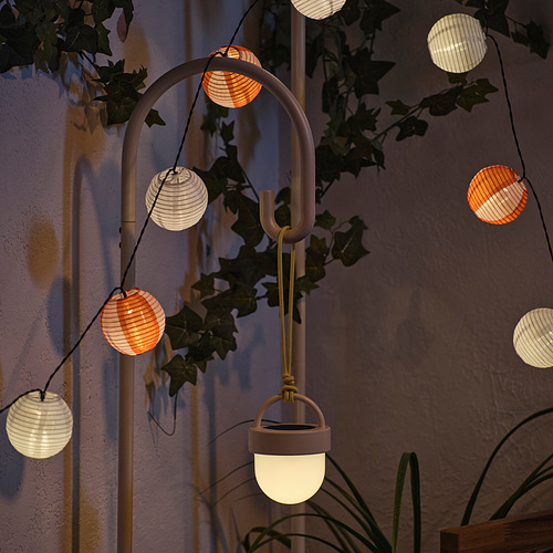 Las linternas que funcionan con energía solar emiten una luz nocturna cálida, se cargan durante el día y se activan automáticamente en la oscuridad, unidas a un soporte de metal curvo con plantas.