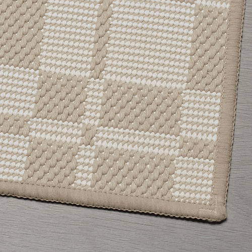 Alfombra de baño texturizada de color beige y blanco con motivos de diamantes, con un borde similar a la gamuza.