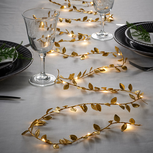 Las elegantes luces de hojas doradas iluminan cálidamente el ambiente de la mesa, agregando un ambiente festivo con una luz blanca suave y cálida.
