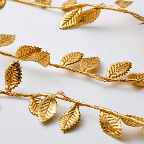 Guirnaldas de luces en forma de pan de oro envueltas entre sí, mostrando intrincados diseños de hojas y una iluminación cálida para la decoración festiva.