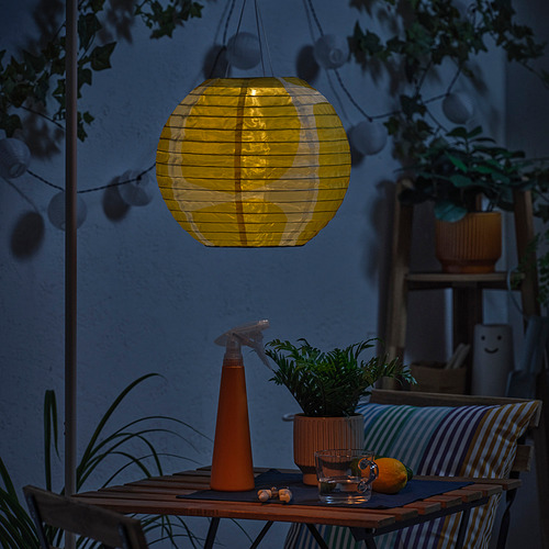 Acogedor patio con linterna solar, planta, naranja y vasos.