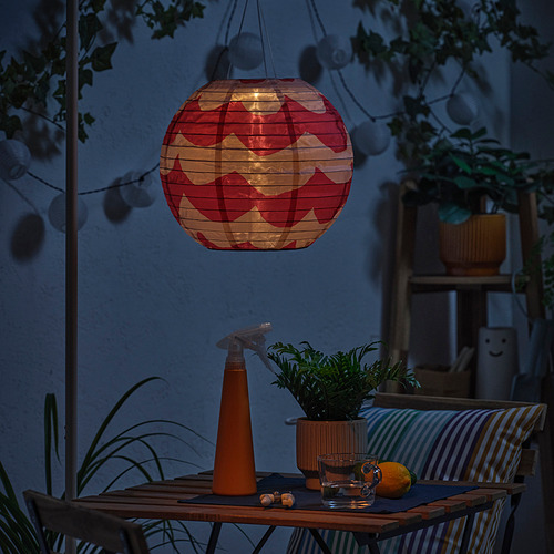 Patio oscuro con farolillo rojo. La mesa tiene planta, vasos, limón. Linterna incandescente.