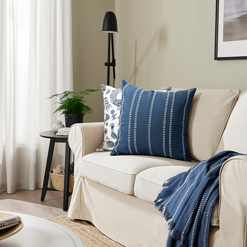 Sofá beige con almohada KRUTBRÄNNARE de rayas azules.