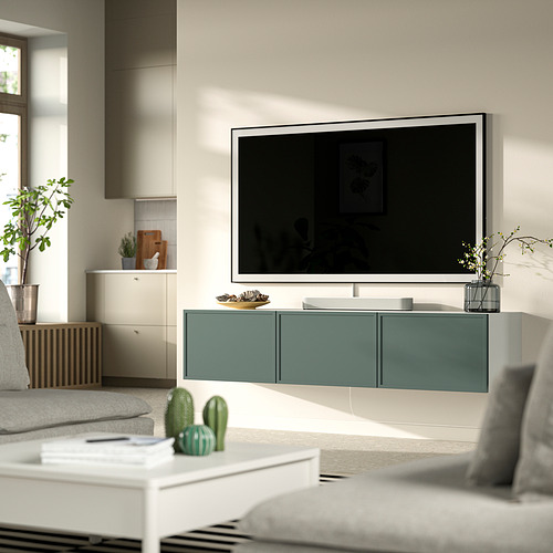 Moderna sala de estar con banco de TV plateado BESTÅ , puertas verdes, sofá gris, mesa de centro blanca y vegetación decorativa.