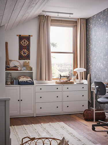 Acogedora oficina en casa con tocador blanco HAUGA, alfombra beige, silla marrón, cortinas beige y tapiz de pared cerca de la ventana.