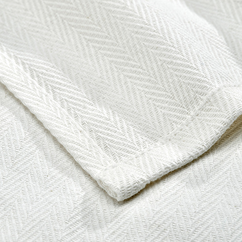 Primer plano de una pila de toallas de algodón blanco prístino, que muestra un detallado tejido en espiga, que indica alta calidad y absorción.