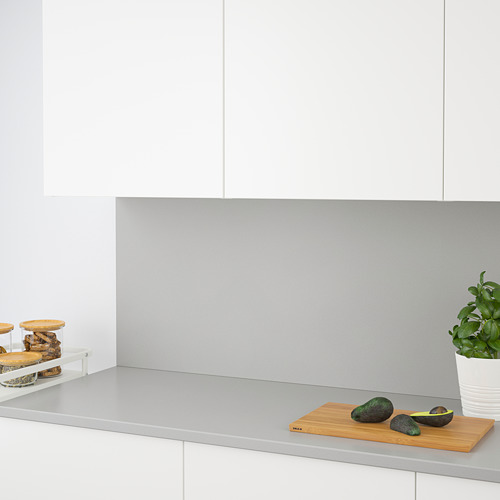 Encimera de cocina moderna con superficie de cuarzo gris, tabla de cortar de madera, aguacates y planta de cuidado.