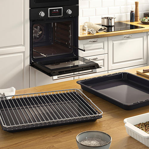 Cocina moderna con horno abierto que muestra rejillas ajustables, bandejas para hornear y un cuenco de arroz en la encimera.