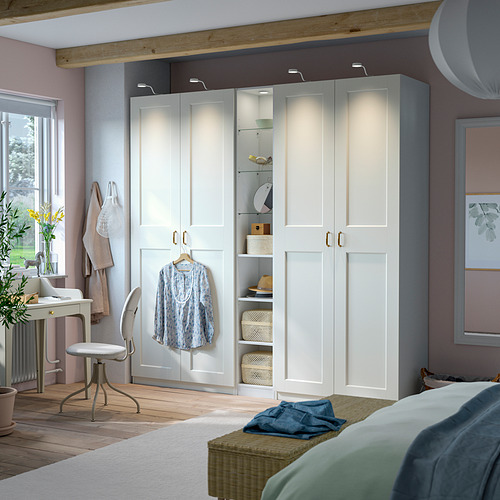 Dormitorio moderno con armario estrecho PAX en blanco, con estantes de vidrio y madera para almacenamiento y exhibición.