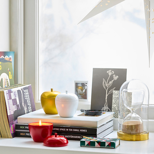 Repisa de la ventana con candelabros VINTERFINT, vela roja, libros, reloj de arena y decoración con luz natural.