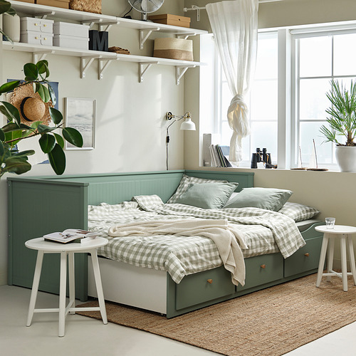 Dormitorio moderno con sofá cama HEMNES, mesas auxiliares y decoración blanca.