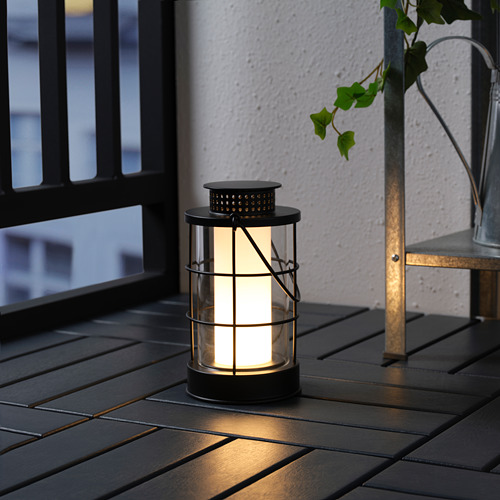 Acogedora linterna negra de exterior sobre una mesa, iluminada con luz led cálida, perfecta para cualquier ambiente nocturno.