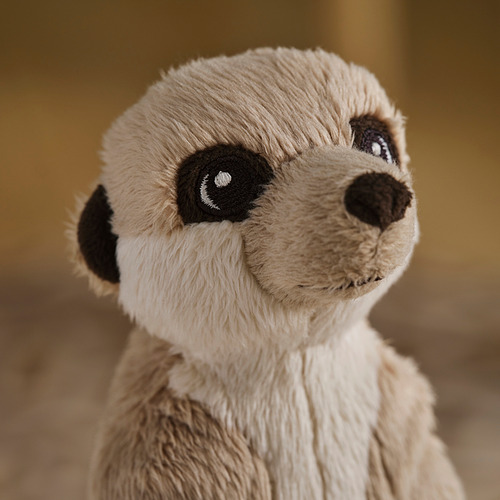 Primer plano de un peluche de peluche, probablemente un oso, con un suave pelaje beige, ojos negros redondos y una sonrisa amable.