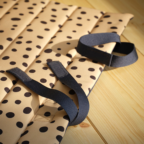Alfombrilla de tela moteada doblada con correas duraderas sobre suelo de madera.