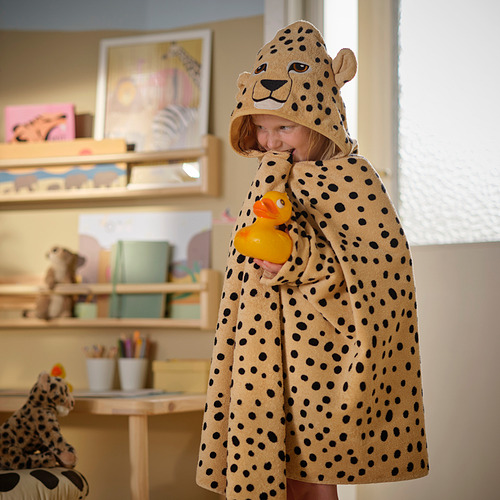 Niño en toalla con estampado de guepardo con pato, cerca de juguetes.