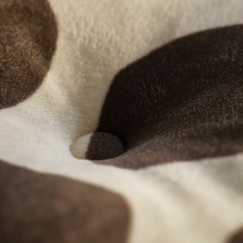 Tejidos suaves y texturizados en beige, negro y marrón. El primer plano muestra la calidad del material afelpado.