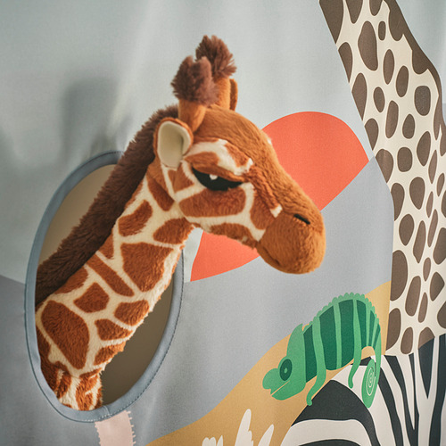 Una jirafa de peluche se asoma a través de una ventana circular azul en la cortina de la cama de los niños, rodeada de vibrantes estampados de safari.
