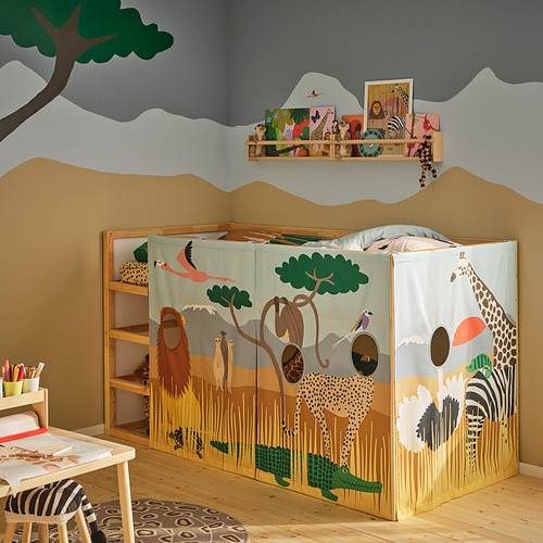 Habitación para niños con cama KURA, cortinas con temática de safari, silla de cebra y estantes para juguetes.