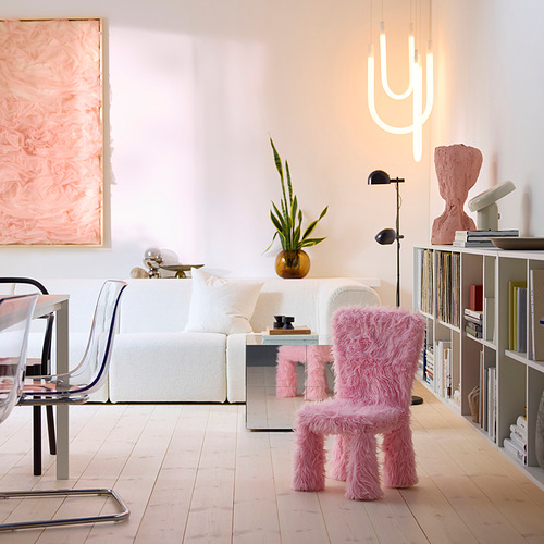 Sala de estar moderna con sofá blanco, silla peluda rosa, estantería y luz de cactus.
