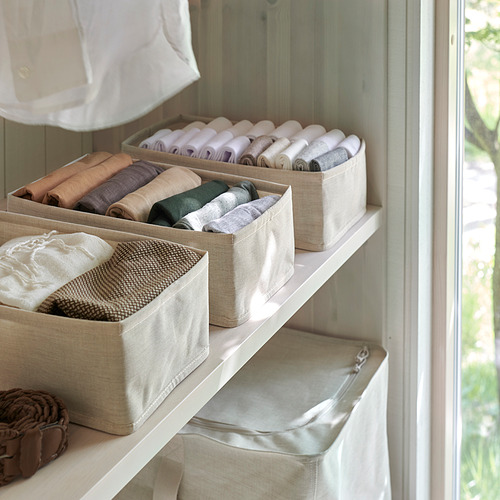 Estantes organizados con ropa doblada en cajas de tela, manteniendo los artículos ordenados y accesibles.