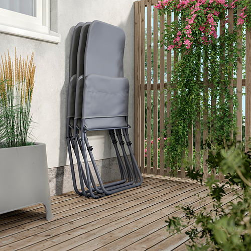 Tumbonas plegables apiladas sobre una terraza de madera. Ideal para relajarse al aire libre, ahorrar espacio y facilitar el almacenamiento. Tela gris y marco metálico.