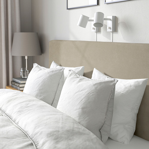 Cama ordenada con sábanas blancas, cabecero gris y lámparas de pared. Alternativa: cama con sábanas blancas, cabecero gris y lámparas de noche.