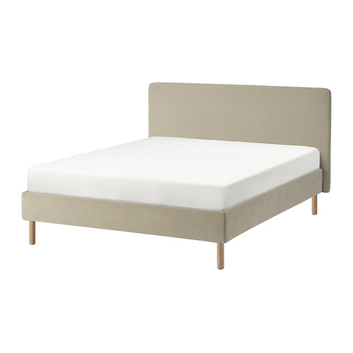 Representa la cama TÄRNKULLEN en color beige. Es un cabecero de felpa, patas de madera y un diseño limpio y minimalista.