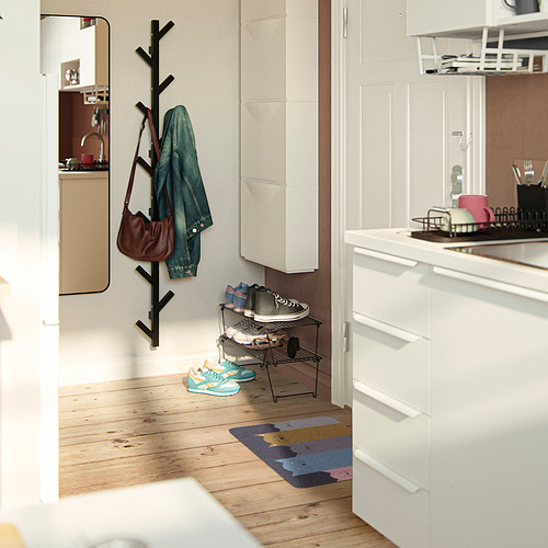 Entrada limpia con esterilla de rayas azules, chaqueta verde en el perchero, armarios blancos.