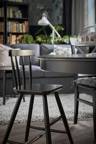 Silla junior negra moderna cerca de la mesa de comedor con pastel.